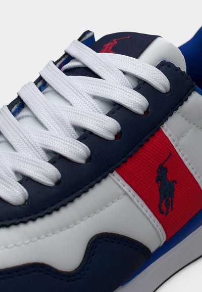 Λευκό αθλητικό παπούτσι με ναυτικό, κόκκινο και μπλε στοιχεία. Διαθέτει υλικά με υφή, λευκά κορδόνια και λογότυπο κοντά στη φτέρνα.