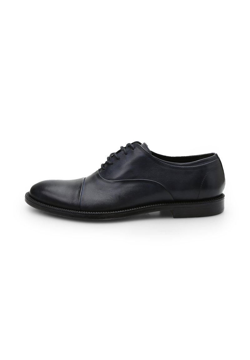 Scarpa elegante in pelle nera con punta rotonda, cucitura sottile sulla punta, design con lacci e tacco basso impilato. Texture liscia e silhouette snella.