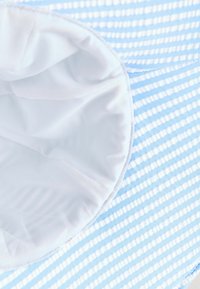 Gestreifter blauer Stoff mit weißen Linien, der ein glattes weißes Innenfutter aufweist. Das Design ist leicht und weich, geeignet für verschiedene Anwendungen.
