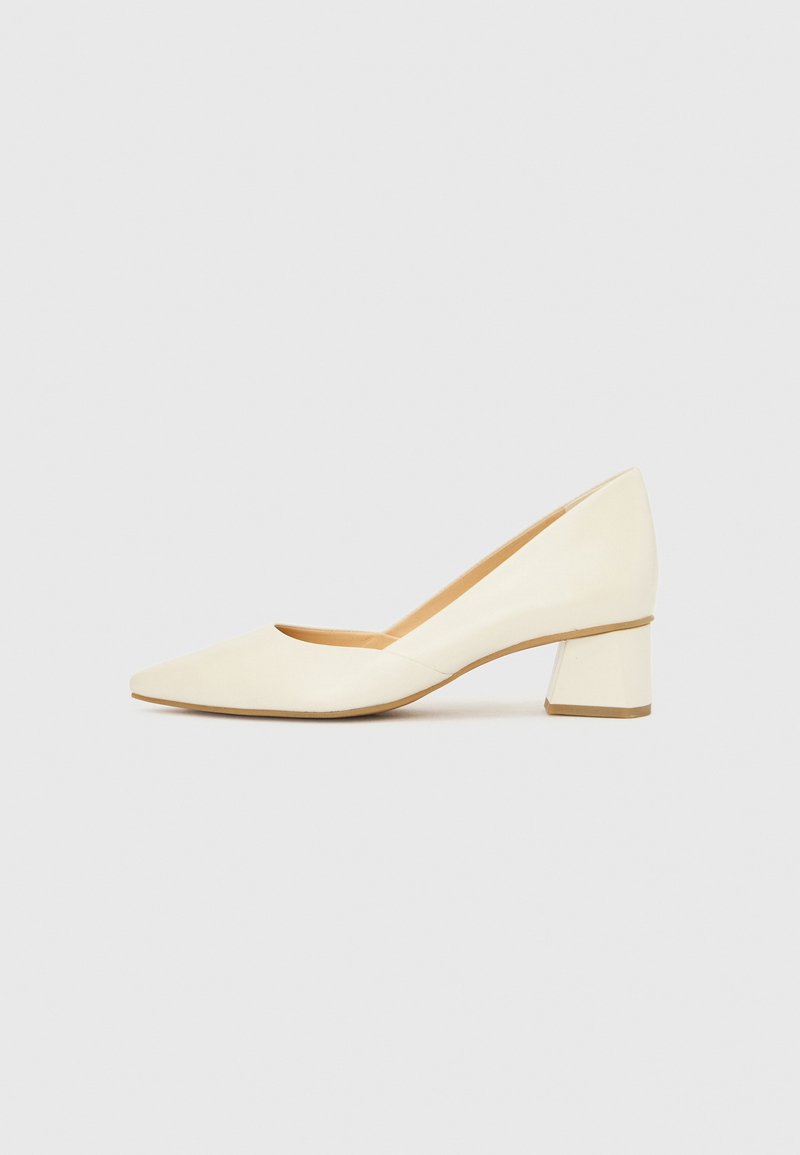 Sapato de salto alto cor creme com biqueira pontiaguda e salto bloco. Textura de couro suave e design minimalista.