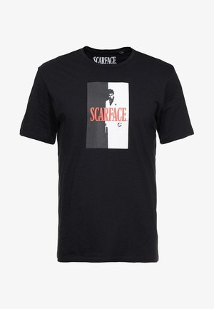 T-shirt noir avec un graphique en noir et blanc d'un homme tenant une arme et le texte rouge "SCARFACE" au centre.