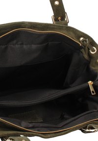 Groene suède tas met gouden ritssluiting, voorzien van een zwart stoffen interieur, twee compartimenten en een extra binnenzak met rits.