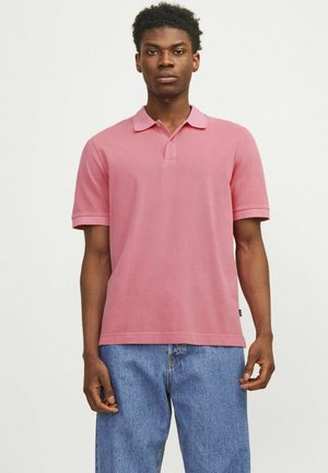 Camisa polo rosa de manga corta con cuello, hecha de algodón, presenta un logo sutil, combinada con vaqueros de denim holgados.