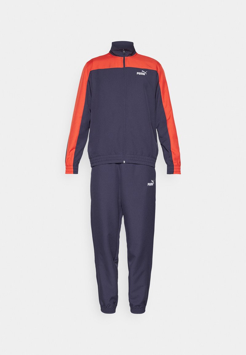 Chándal en azul marino y rojo que incluye una chaqueta con cremallera y pantalones con cintura elástica, fabricado en tela suave con el logo de Puma en ambas piezas.