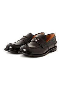 Black leather loafers with a smooth finish, featuring a decorative strap and logo hardware, rounded toe, and contrasting sole stitching.