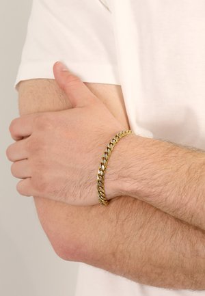 Goldfarbener Kettenarmreif mit ineinandergreifenden Gliedern, am Handgelenk getragen. Glatte Oberfläche mit reflektierendem Finish, das die detaillierte Handwerkskunst präsentiert.