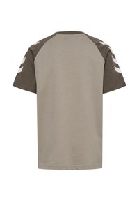Kortärmad t-shirt i ljus beige, med mörkt olivgröna raglanärmar. Har vita chevronränder på vänster ärm. Mjuk bomullsmaterial.