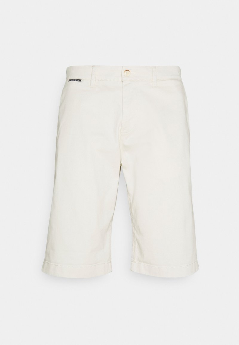 Shorts en coton beige à coupe droite, ourlets roulés et une seule étiquette décorative près de la ceinture. Comprend une fermeture par bouton et des poches.