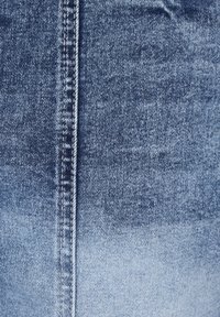 Tela de mezclilla con un degradado de azul oscuro a azul claro, con una costura central y un hilado blanco en contraste a lo largo de los bordes.