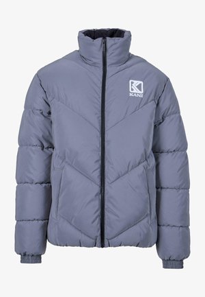 Hallhalli hallwiniga, millel on kõrge krae, lukuga sulgemine ja chevron-muster. Omab elastseid mansette ja logo vasakul ülapeal.