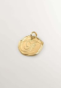 Colgante en tono dorado con forma irregular y ondulada, que presenta una letra "F" en relieve y un pequeño aro para su sujeción.