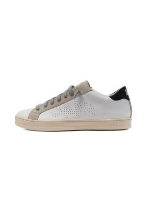 Zapatilla deportiva de cuero blanco con detalles de ante beige, cordones grises, patrón perforado en el lateral, suela beige y lengüeta trasera negra con logo.