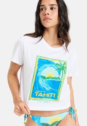 T-shirt blanc à manches courtes avec un graphisme tropical représentant des vagues, un soleil et des palmiers en vert et bleu, associé à un bas de bikini bleu.