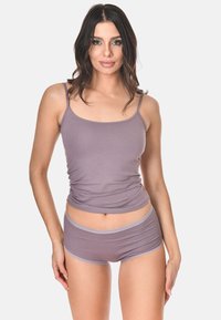 Maglietta senza maniche viola con spalline sottili, abbinata a pantaloni corti coordinati. La texture liscia e il design aderente mettono in risalto uno stile casual per il tempo libero.