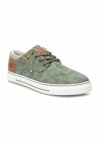 Le sneakers in tela verde presentano una tomaia texture, accenti marroni e suole in gomma bianca con strisce rosse e blu. I lacci marroni completano il design.