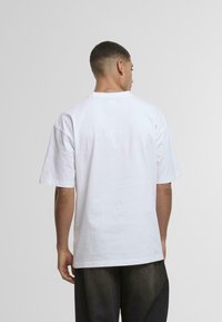 Hvid bomulds T-shirt med en afslappet pasform, korte ærmer og rund hals. Har en glat overflade og minimale syninger.
