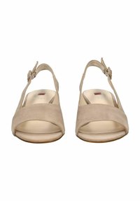 Sandalias slingback de ante beige con punta abierta, amplia correa frontal, hebilla ajustable y forro interior suave. Suela plana con textura mínima.