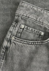 Pilko džinsinio audinio su matomu kišeniu, sidabrinėmis metalinėmis detalėmis, kontrastinga siuvimo, ir blankia tekstūra.