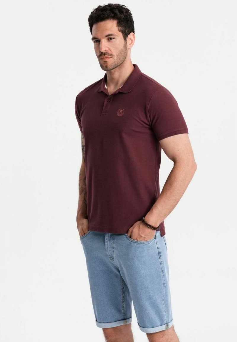 Bordová polo košile s klasickým límcem a vyšitým logem; zkombinována se světle modrými džínovými šortkami s ohrnutými lemy.