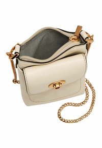 Romantische leren schoudertas van roomkleur met een gouden kettingband, voorzien van een magnetische drukknoopsluiting en een gevoerde binnenkant. Het ontwerp is compact en vierkant van vorm.