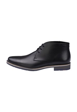 Black leather lace-up ankle boot with a low heel and contrasting stitching on the sole, shown from the side on a white background.