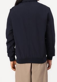Marine bomberjakke med en glat tekstur, elastisk talje og manchetter. Har et rent, minimalistisk design uden synlige mærker.