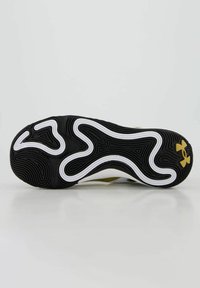 Suola di scarpa sportiva in bianco e nero con texture ondulata. Presenta un logo dorato e un complesso motivo di battistrada per la trazione.