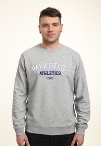 Szary sweter z bawełny, z ribbowymi mankietami i dołem. Na przodzie w ciemnoniebieskim kolorze znajduje się napis "PARK FIELDS ATHLETICS 1961".