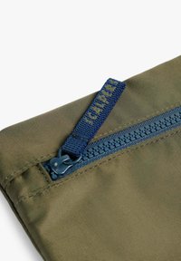 Bolsa de tela verde oliva con un cierre azul, que cuenta con un tirador texturizado y costuras de contraste a lo largo del borde del cierre.