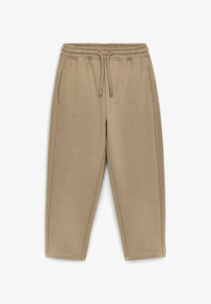 Pantalon de jogging beige avec taille élastique et cordon, doté de poches latérales et jambes droites, conçu pour un usage décontracté.