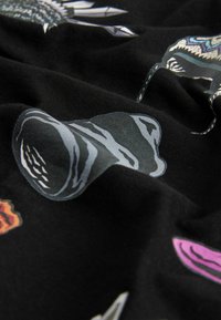Tessuto nero con diverse stampe grafiche, tra cui forme astratte e motivi in tonalità di grigio, rosa e arancione. Trama liscia.