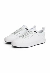 Weiße Sneakers mit einer glatten Lederoberfläche, ausgestattet mit grauen Schnürsenkeln, einer erhabenen Gummisohle und einem kleinen Logo auf der Zunge.