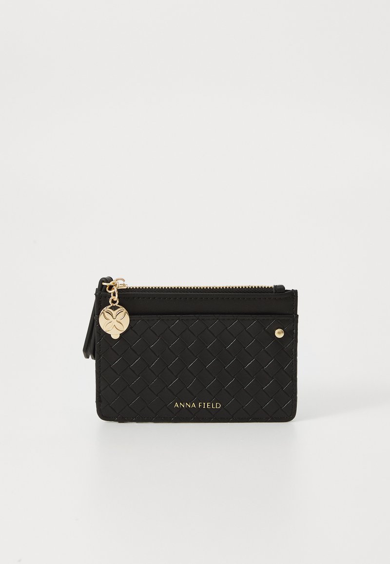 Portefeuille en cuir tissé noir avec fermeture éclair dorée, logo et accent charmant. Présente une texture lisse et est équipé de fentes pour cartes.
