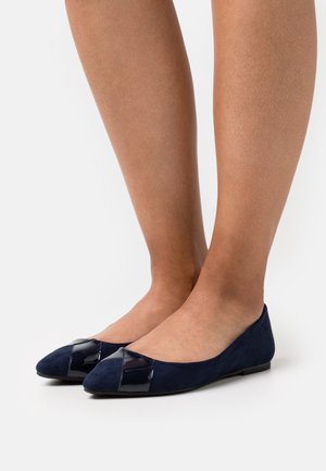 Ballerines en daim bleu marine avec une finition en cuir verni noir brillant au niveau de l'orteil. Elles présentent une forme pointue et une semelle plate.