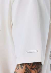 Witte t-shirt met korte mouwen van gladde stof, met een zilveren logo-label op de mouw en een ontspannen pasvorm.