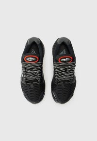 Chaussures de sport noires avec une tige en mesh, accents gris, détails réfléchissants et un bout arrondi, arborant le branding "ClimaCool".