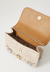 Borsa a mano intessuta in crema con una finitura texturizzata, dotata di chiusura a scatto magnetico e un interno in pelle marrone chiaro con una tasca con zip.