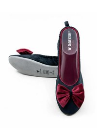 Chaussures slingback noires avec un nœud en velours bourgogne, bout rond, dessus en tissu texturé et semelle en caoutchouc grise. Marquage "GLOVE STORY" à l'intérieur.