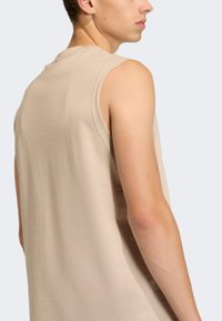 Bež top bez rukava s opuštenim krojem, izrađen od mekanog materijala, s okruglim izrezom i minimalnim detaljima šavova na ramenima.