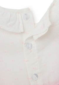 Blusa de algodón blanca con cuello con volantes, estampado de puntos rosas y ribete en rosa claro. Abotonada con botones de plástico blanco.
