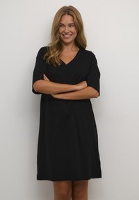 Abito nero con scollo a V realizzato in morbido tessuto, caratterizzato da maniche corte e una vestibilità comoda, con orlo dritto e spacchi laterali per facilitare i movimenti.