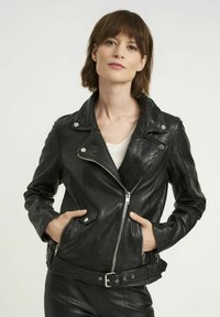Czarna skórzana kurtka motocyklowa z asymetrycznym zamkiem, kołnierzem zapinanym na napę i paskiem w talii. Posiada dwie boczne kieszenie na zamek i gładką fakturę.