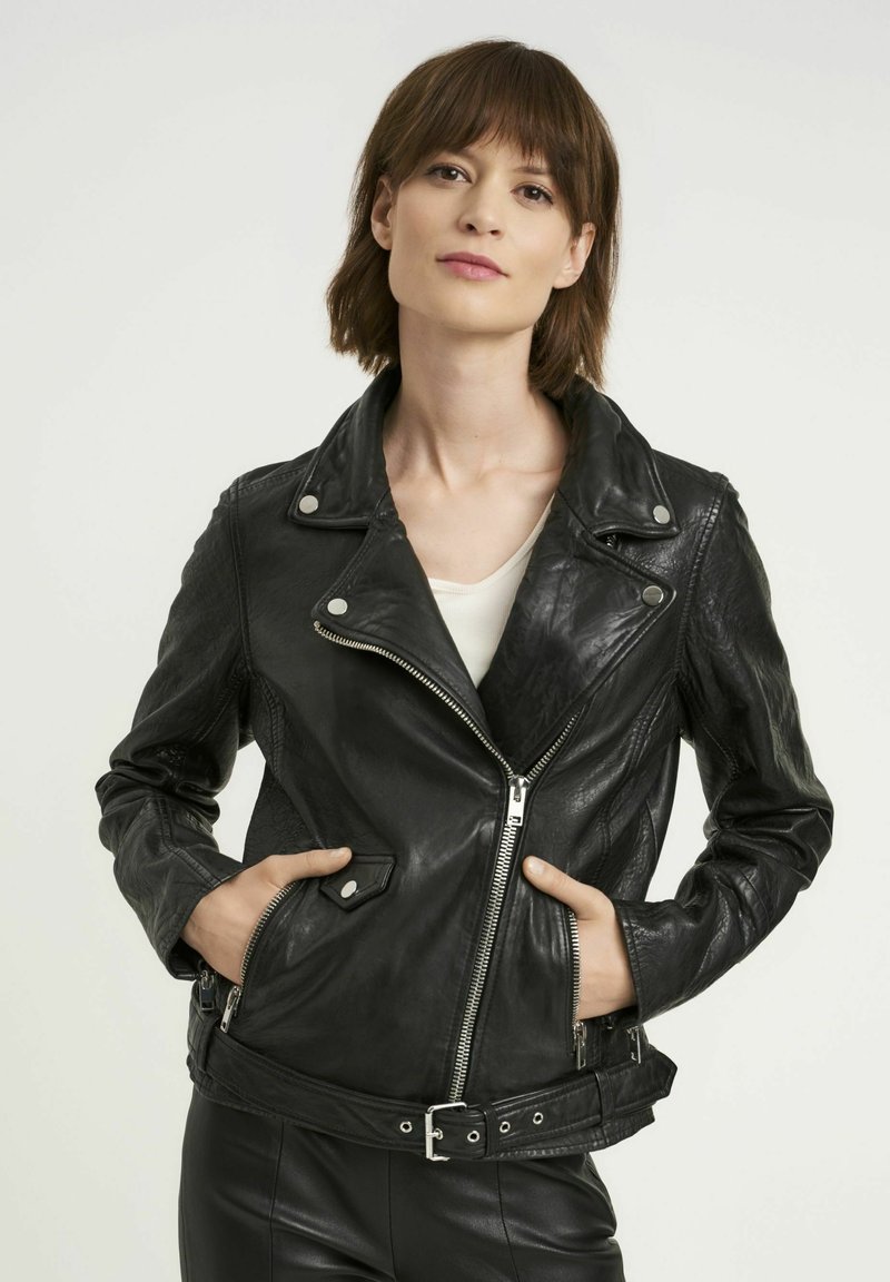 Czarna skórzana kurtka motocyklowa z asymetrycznym zamkiem, kołnierzem zapinanym na napę i paskiem w talii. Posiada dwie boczne kieszenie na zamek i gładką fakturę.