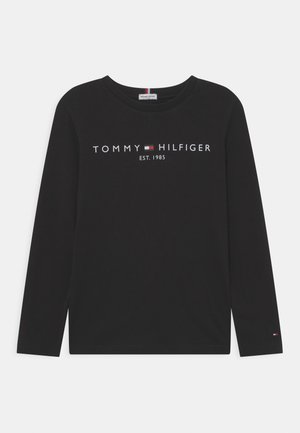 Camisa de manga larga negra de algodón con escote redondo. Presenta el logotipo "TOMMY HILFIGER" y "EST. 1985" en impresión blanca y roja.