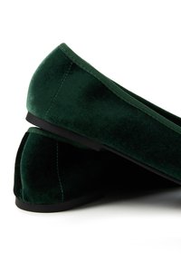 Bailarinas de terciopelo verde con una textura suave, punta redondeada y suela negra. El diseño es clásico y de perfil bajo, con detallados suturas sutiles.