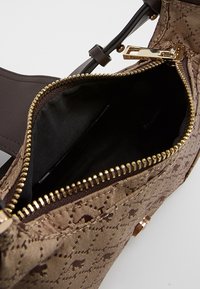 Borsa a tracolla marrone con motivo, zip dorata, aperta per mostrare l'interno foderato in nero e la tracolla in pelle marrone scuro con hardware dorato.