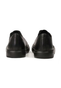 Mustad nahast tossud sileda tekstuuriga, madala disainiga ja kummist tallaga. Omavad õmblustega aktsente ja ümmargust varbaosa.