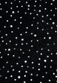 Tessuto nero impreziosito da borchie argentate lucenti di varie dimensioni, distribuite in modo sparso per creare un motivo decorativo e strutturato.