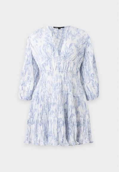 Robe plissée blanche avec motifs floraux bleu clair, manches longues bouffantes, taille cintrée et jupe à étages.
