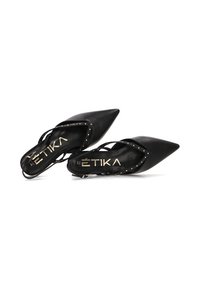 Zapatos de tacón negros de cuero con tira al talón y punta afilada, decorados con tachuelas a lo largo de los laterales y una textura suave.